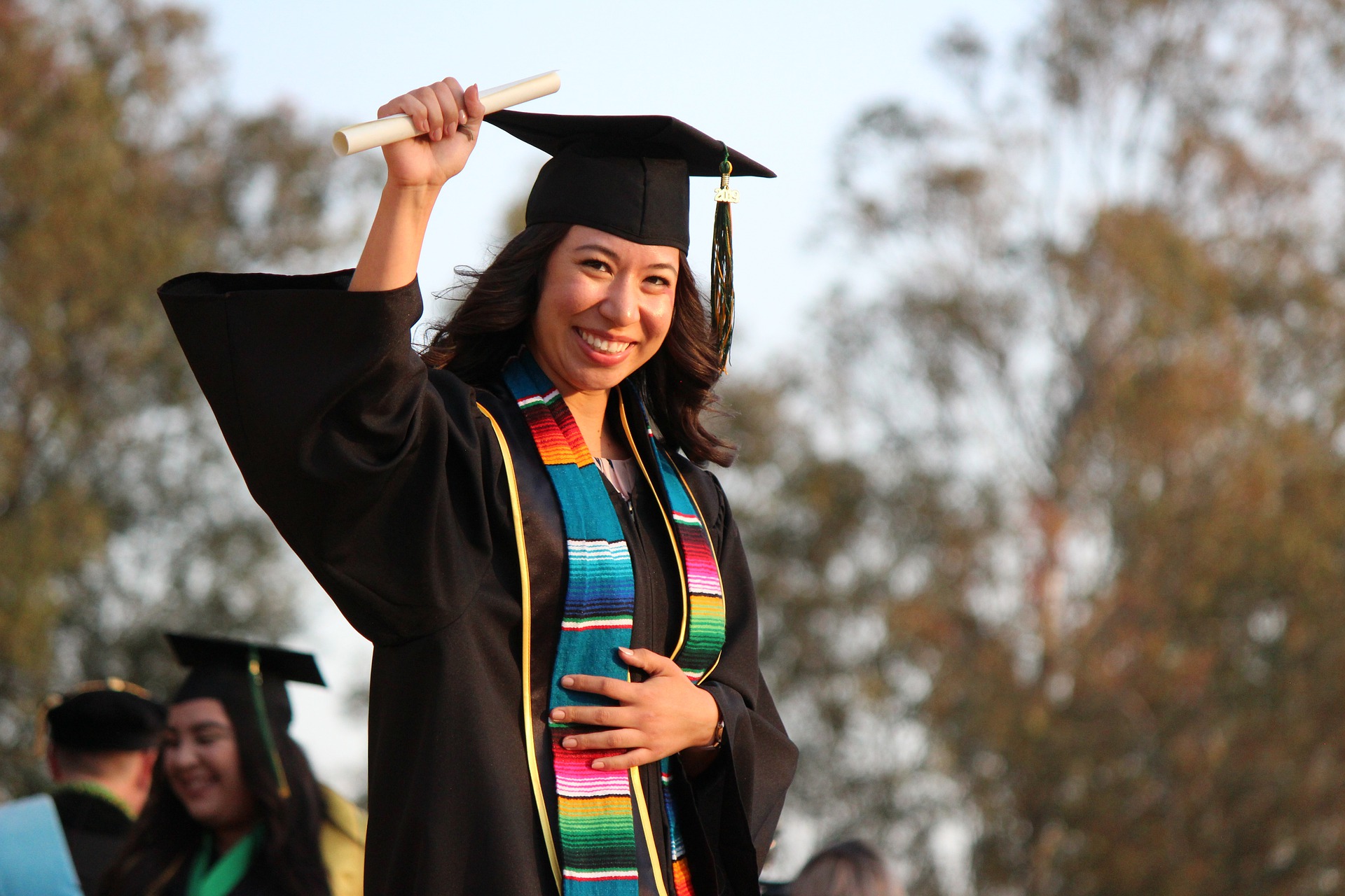 A graduate holds up her diploma in celebration